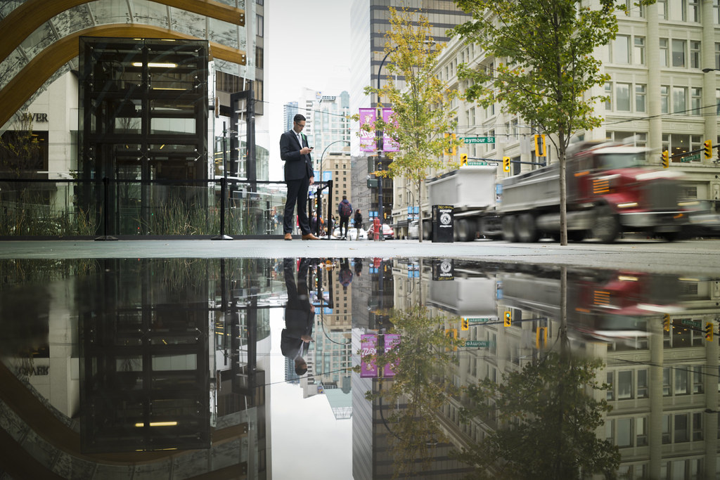 A truck reflected in still water beside office buildings